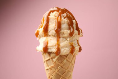 Renkli arkaplanda karamel soslu lezzetli dondurma, yakın plan.