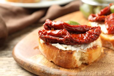 Krem peynirli lezzetli bruschettalar, güneşte kurutulmuş domatesler ve yeşil zeytinler masada, yakın plan.