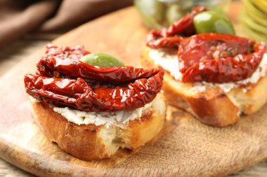 Krem peynirli lezzetli bruschettalar, güneşte kurutulmuş domatesler ve yeşil zeytinler masada, yakın plan.