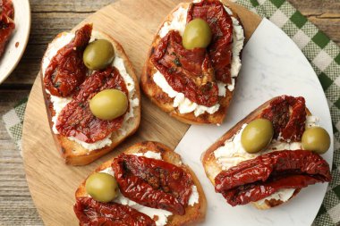 Krem peynirli nefis bruschettalar, güneşte kurutulmuş domatesler ve yeşil zeytinler masanın üstünde.