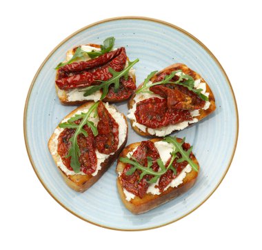 Krem peynirli lezzetli bruschettalar, güneşte kurutulmuş domatesler ve beyaza izole edilmiş roka.