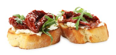 Krem peynirli lezzetli bruschettalar, güneşte kurutulmuş domatesler ve beyaz üzerine izole edilmiş roka.