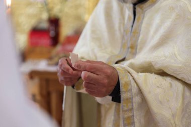 Kilisede elinde bir kağıt parçası tutan rahip, yakın plan.