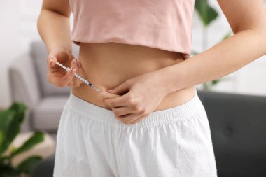 Tüp bebek için. Kadın karnına iğne yapıyor, kapalı alanda, yakın çekim.