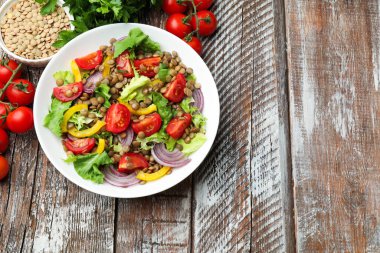 Lezzetli mercimek salatası ve ahşap masa üzerindeki malzemeler, düz yatak. Metin için boşluk