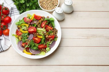 Lezzetli mercimek salatası ve hafif ahşap masa üzerindeki malzemeler, düz yatak. Metin için boşluk