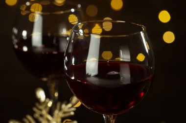Mutlu Noeller ve mutlu yıllar. Arka planda kırmızı şarap kadehleri, bulanık ışıklar, yakın plan.