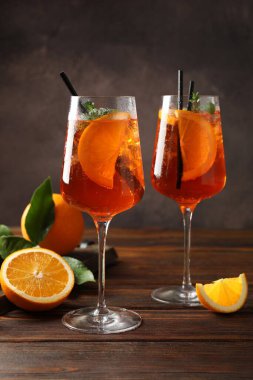 Serinletici spritzer kokteyli ve portakallar ahşap masada.