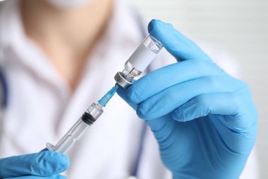 Hemşire şırıngayla aşıyı şişeden alıyor, yakın plan.