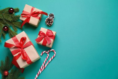 Paketlenmiş Noel hediyeleri ve yeşil arka planda dekorasyon, düz yatış. Metin için boşluk