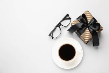 Güzel bir hediye kutusu, bardaklar ve beyaz arka planda bir fincan kahve, düz bir yatak. Metin için boşluk