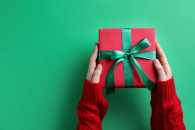 Yeşil arka planda Noel hediyesi olan bir kadın. Metin için boşluk