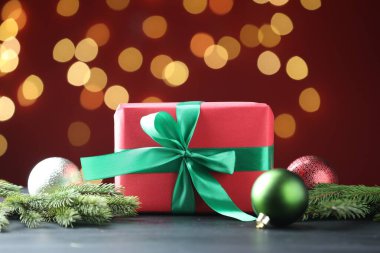 Paketlenmiş hediye ve Noel dekoru siyah masanın üzerinde kırmızı arka planda Bokeh etkisi ile, yakın plan. Metin için boşluk