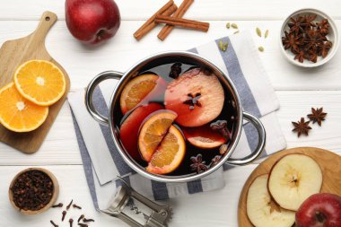 Lezzetli sıcak şarap tencerede ve malzemeler beyaz ahşap masada, düz yerde.