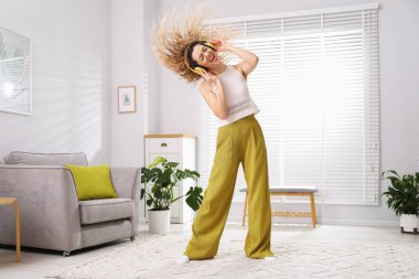 Kulaklıklı mutlu kadın evde dans ediyor.