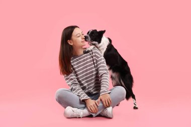 Pembe arka planda sevimli Sınır Köpeği Collie köpeği olan bir kadın.