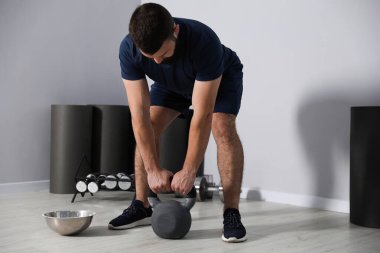 Spor salonunda kettlebell ile egzersiz yapan güçlü bir adam.
