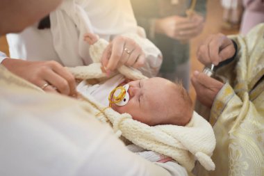 Anne, vaftiz töreninde çocuğunu kucağında tutuyor.