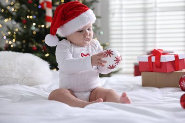 Evde yatağında takı olan Noel Baba şapkalı şirin bir bebek. Noel sezonu