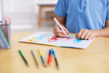 Ahşap masada aile çizen şirin küçük çocuk, yakın plan.