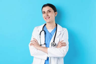 Açık mavi arka planda steteskobu olan tıp üniformalı bir doktor.