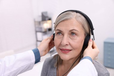 Duyma testi. Doktor klinikte hastanın işitsel kulaklıklarını ayarlıyor.