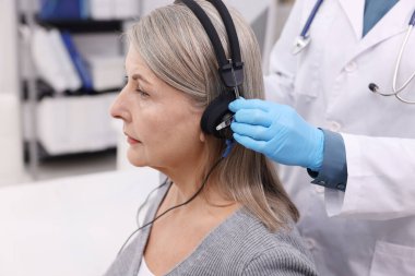 Duyma testi. Doktor klinikte hastanın işitsel kulaklıklarını ayarlıyor.