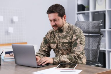 Askeri eğitim. Asker üniforması içindeki öğrenci ahşap masada öğreniyor.