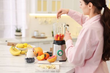 Mutfaktaki beyaz mermer masada blender ile nefis smoothie yapan bir kadın. Metin için boşluk