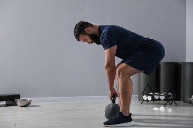Güçlü adam spor salonunda kettlebell ile egzersiz yapıyor, mesaj için yer var.
