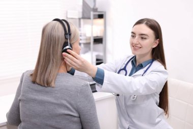 Duyma testi. Doktor klinikte hastanın işitsel kulaklığını ayarlıyor.