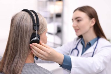 Duyma testi. Doktor klinikte hastanın işitsel kulaklığını ayarlıyor.