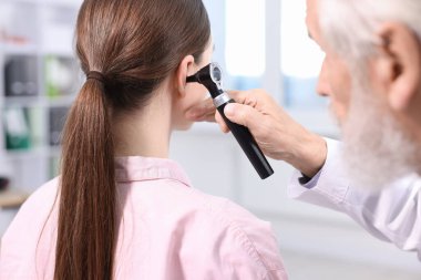 Duyma testi. Klinikte otoskopla hastanın kulağını muayene eden doktor, yakın plan.