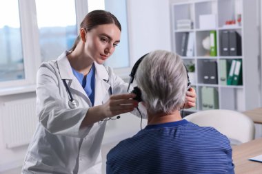 Duyma testi. Doktor klinikte hastanın işitsel kulaklığını ayarlıyor.