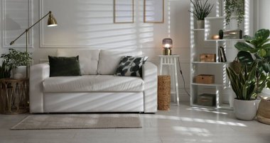 Rahat bir kanepe, diğer mobilyalar ve kapalı alandaki yeşil bitkiler. İç tasarım