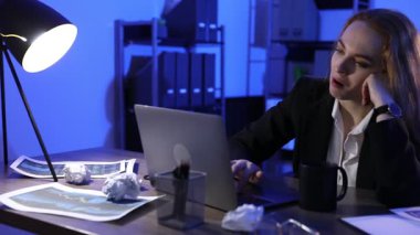 Yorgun bir kadın geceleri ofiste uyukluyor. Kamera sağa hareket ediyor