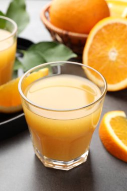 Taze portakal suyu ve meyveler gri masada, yakın plan.