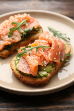 Somon, avokado, roka ve tahtadan masada susam tohumlu lezzetli bruschetta.