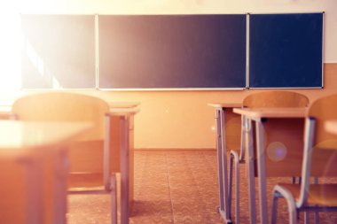 Güneşli bir günde kurul, sandalye ve masalarla dolu bir sınıf seçici bir odak noktası.