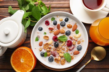 Sağlıklı kahvaltı. Fındıklı yulaf ezmesi, böğürtlen ve süt kasede ahşap masada servis edilir.