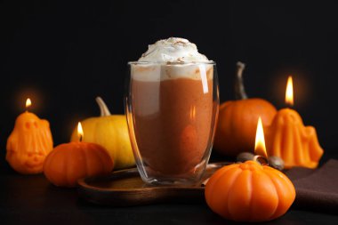 Krem şantili balkabaklı latte ve siyah arka planda sonbahar dekoru, yakın plan.