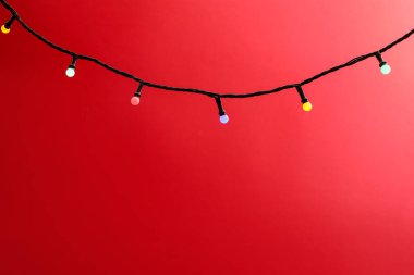 Kırmızı arka planda parlak Noel ışıkları, yakın plan. Metin için boşluk