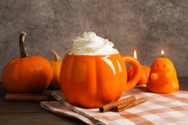 Balkabaklı latte, fincanda krema ve ahşap masada sonbahar dekoru, yakın plan.