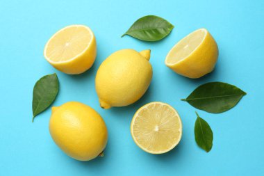Taze olgun limonlar ve açık mavi arka planda yapraklar.