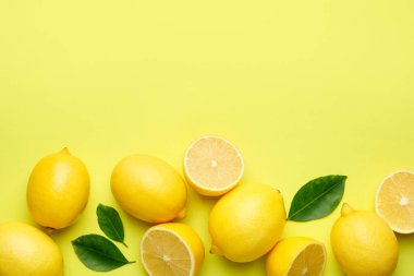 Taze olgun limonlar ve sarı arka planda yapraklar, düz. Metin için boşluk