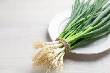 Beyaz ahşap masada taze taze taze soğanlar, yakın plan. Metin için boşluk