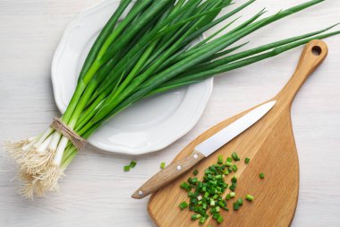 Taze taze soğan ve bıçak beyaz ahşap masada, düz yatıyordu.