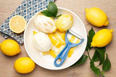 Lezzetli taze limonlar, soyucu ve yapraklar ahşap masa, düz uzanmış