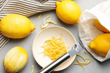 Taze limonlar, keyifli ve zester aletli gri masada, düz yerde.