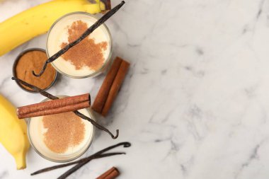 Lezzetli protein karışımı bardaklarda, muzlarda, tarçınlarda ve beyaz mermer masada vanilyalı kapsüllerde, düz yerde. Metin için boşluk